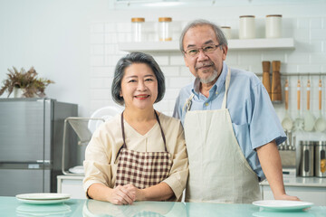 Fototapeta premium Portrait of Asian grandparents couple smiling, standing in the kitchen