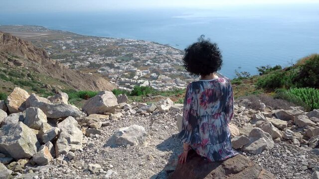 Tourist woman with dress enjoy view of Kamari from high Ancient Thera on mounain