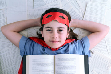 Young superhero girl reading a book