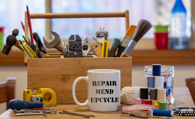 Repair Mend upcycle on a mug surrounded by repair tools on table in café used as a repair centre, consumer activism to repair household items to reduce waste and support a sustainable lifestyle