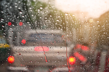 Raindrops run down on car windshield from inside view. Traffic jam during the heavy rain storm.