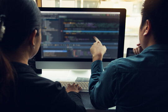 Two software developers are analyzing together about the code written into the program on the computer.