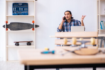 Young man repairing skateboard at workshop