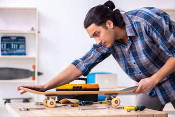 Young man repairing skateboard at workshop