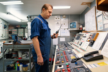 Marine Engineer working on radio communication at Engine Control room ECR. Vessel communication with VHF and UHF walkie-talkie radio. Start or stop of main engine