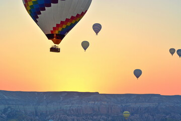 flying air balloons with tourists in basket in sky over morning valley in Turkey, Cappadocia with sunrise