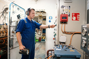 Marine engineer officer controlling vessel enginesand propulsion in engine control room ECR. Ship onboard maintenance
