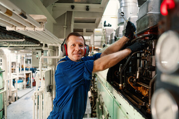 Marine engineer officer controlling vessel enginesand propulsion in engine control room ECR. Ship...