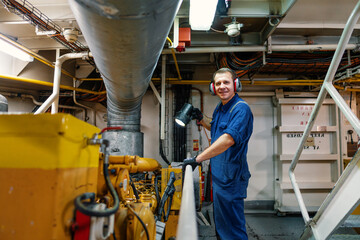 Marine engineer officer controlling vessel enginesand propulsion in engine control room ECR. Ship...