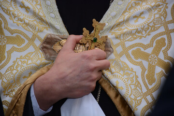Priest hands close-up at church, holding a cross, Christian ceremony