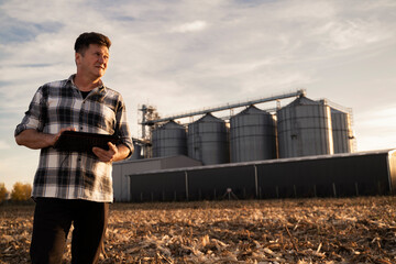 Man with tablet in his hands standing in front of agricultural silos  © phoenix021