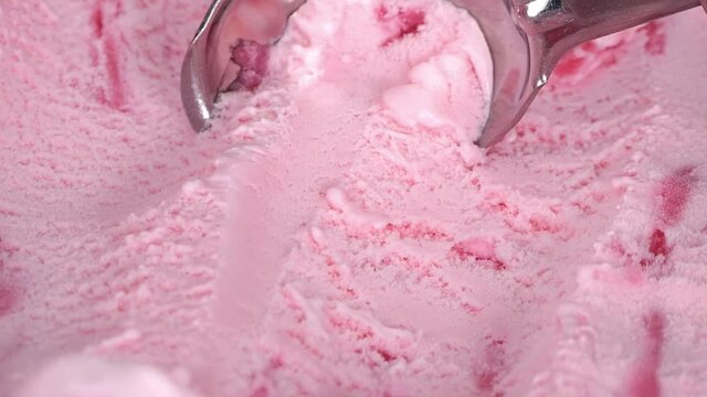 Close up Slow motion steel ice cream scoop is scooping Strawberry flavor ice cream meat.

