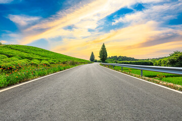 Fototapeta premium Countryside asphalt road and green tea plantations with mountain natural scenery in Hangzhou at sunrise.