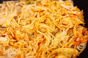 spaghetti mixed with fried tomato heating in a pan