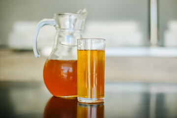 Apple juice in a glass and in a glass teapot. A jug with a yellow beverage drink. Sea buckthorn fruit drink. Clear glass