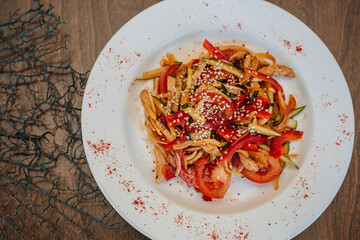 Spicy salad with cucumbers and tomatoes, bell pepper and sesame seeds. Diet food. On a white plate. Dish on a dark background.