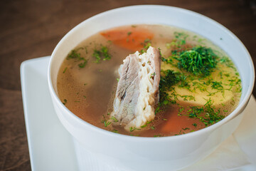 Diet soup with a small piece of pork and potatoes. Lean broth. Nutrition for gastritis. White bowl on a dark background