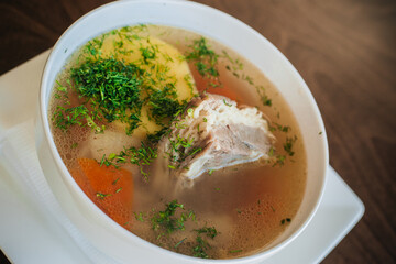Diet soup with a small piece of pork and potatoes. Lean broth. Nutrition for gastritis. White bowl on a dark background