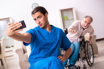Old man in wheel-chair and young bad caregiver indoors