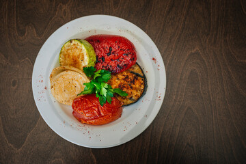 Baked vegetables. Grilled eggplants with tomatoes and zucchini. Vegetarian food. White dish on a dark background