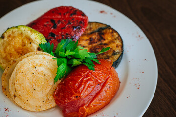 Baked vegetables. Grilled eggplants with tomatoes and zucchini. Vegetarian food. White dish on a dark background