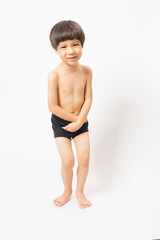 Fototapeta premium Cute little Asian 3 years old toddler boy wearing black shorts standing on white background.