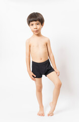 Fototapeta na wymiar Cute little Asian 3 years old toddler boy wearing black shorts standing on white background.