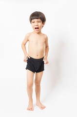 Obraz premium Cute little Asian 3 years old toddler boy wearing black shorts standing on white background.
