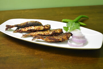 a plate of tasty and yummy fish fry on a wooden table