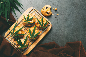 cannabis cookies and cannabis leaves put on wooden cutting board