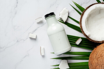 the bottle of coconut milk put on white marble background