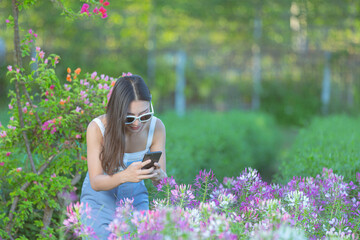 Woman using mobile phone to take photo in the flower garden.