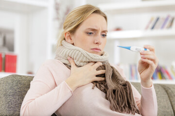 exhausted woman having fever and checking temperature