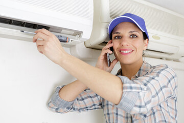 Fototapeta na wymiar female operator using smartphone and repairing air conditioning