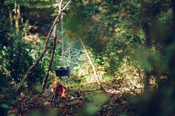 Cast iron pot cooks over open fire in a campsite
