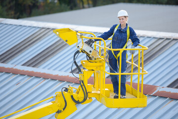 female worker elevated in cherry picker bucker