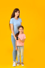 Mother and her diabetic daughter with glucometer on color background