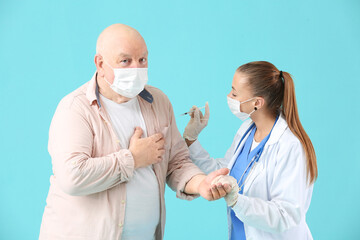 Doctor giving senior diabetic man insulin injection on color background