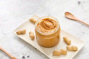 Jar with tasty peanut butter on table