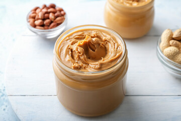 Jar with tasty peanut butter on table