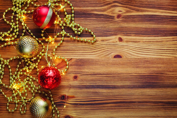 Christmas decorations, gold beads and Christmas balls on an old wooden brown background with a copy of the text space