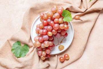 Plate with sweet ripe grapes on color background