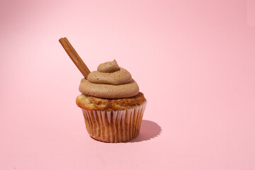 Cinnamon cupcake with frosting and s cinnamon stick on a white pedestal