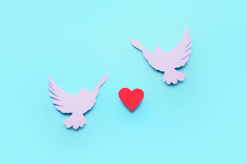 Paper doves and heart on color background. International Day of Peace