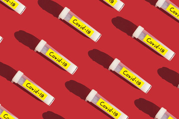geometric pattern on a red background. tube with coronavirus vaccine. pandemic treatment