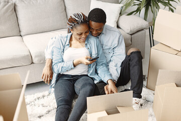 Young couple moving in to new home together. African american couple with cardboard boxes.