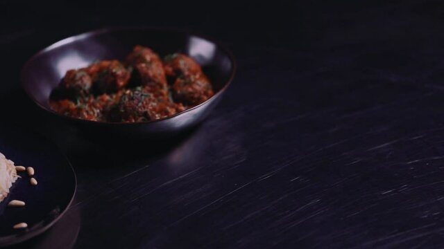 Dawood, Daoud Basha Dish - Plate Of Vermicelli Rice Garnished With Pine Nuts And A Bowl Of Meatballs In Tomato Gravy Served On A Table. - close up, sliding shot