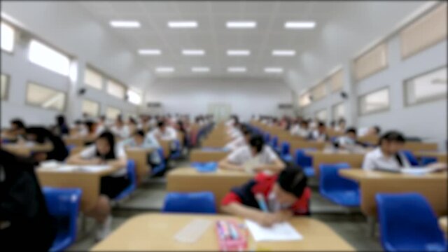 Blurred Time Lapse of Asian students taking an exam in classroom