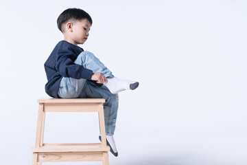 Asian boy wearing socks by himself