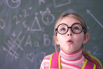 Smart little girl wearing big glasses while using her laptop computer